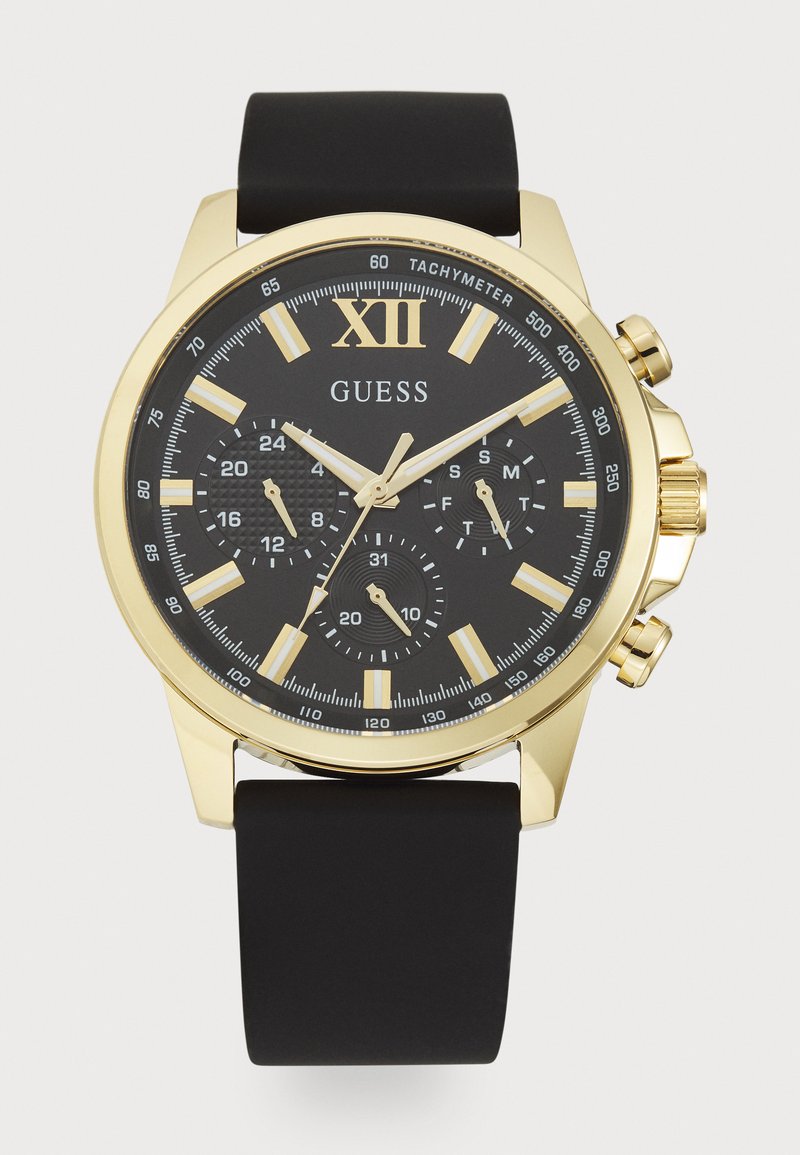 Montre chronographe noire avec un boîtier doré, dotée d'un cadran noir, de marqueurs horaires blancs et d'un bracelet en caoutchouc. Échelle tachymétrique remarquable présente.