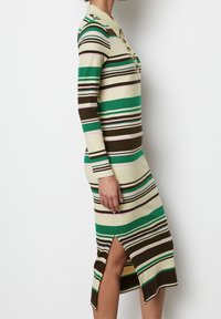 Kardiganująca sukienka do kolan z kołnierzykiem, z naprzemiennie ułożonymi paskami w kolorach zielonym, brązowym, różowym i kremowym, z bocznym rozcięciem dla swobody ruchów.