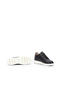Zapatillas de cuero negras con suela de goma blanca, con tachuelas de metal redondas en el lateral, diseño con cordones y cuello acolchado para mayor comodidad.