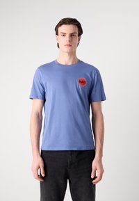 Light blue short-sleeve T-shirt made of cotton, featuring a round neckline and a red circular logo with "HUGO" on the left chest.