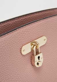 Różowa, teksturowana skórzana torebka na ramię z złotym zameczkiem i detalami w kolorze złotym. Posiada gładkie czarne wykończenie wzdłuż górnej krawędzi.