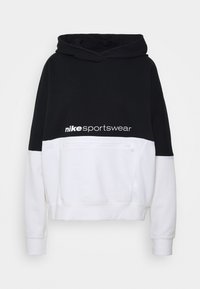 Svart och vit Nike sporttröja med huva, featuring en framficka med dragkedja, långa ärmar och en kort design. Logotyp visad på bröstet.