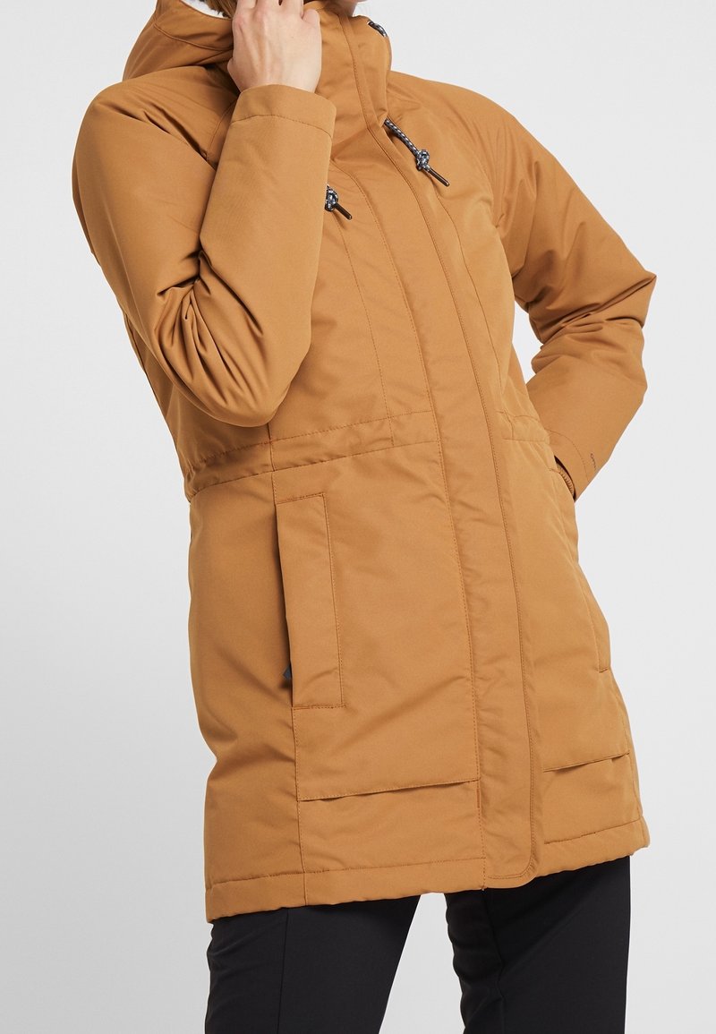 Brązowa ocieplana parka z wysokim kołnierzem, regulowanymi sznurkami, bocznymi kieszeniami i gładką teksturą. Średniej długości konstrukcja zapewniająca ciepło.