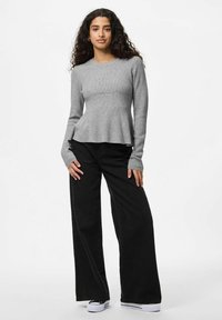 Haut à manches longues gris à côtes avec un ourlet évasé, associé à un pantalon large noir et des baskets noir et blanc. Design simple, texture douce.