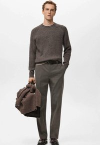 Brązowy prążkowany sweter z dzianiny, szare spodnie, czarny pasek i czarna torba z brązowym dzianinowym elementem przewieszonym przez ramię. Gładka faktura, klasyczny krój.