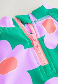 Tvåfärgad baddräkt med ett grönt och rosa blommönster. Har en rosa dragkedja och en hög krage för mer täckning.