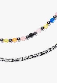 Två halsband: ett med färgglada runda pärlor i rosa, blått, grönt, gult, orange och svart; det andra ett blanka silverkedja med ovala länkar.