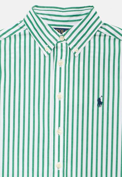 Camisola de manga comprida às riscas verdes e brancas, com colarinho abotoado e bordado de logótipo. O tecido tem uma textura suave; os botões são de cor clara.