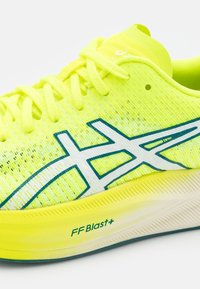 Neon žlutá běžecká bota s texturovaným svrškem, odpovídajícími šněrováním a modrými akcenty. Obsahuje polstrovanou střední podrážku FF Blast+.