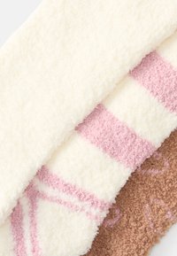 Drei weiche Fleece-Socken: eine cremefarbene mit strukturierter Oberfläche, eine rosa mit Streifenmuster und eine braune mit subtilen Blumenmotiven. Weich und dick.