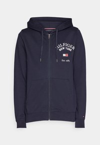 Sudadera con cremallera en azul marino hecha de mezcla de algodón, con un logo impreso en el frente, dos bolsillos laterales y capucha con cordón y puños acanalados.