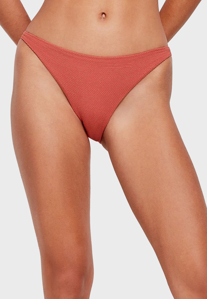 Slip di bikini rosso a coste con un design a vita bassa e copertura minimale, con bordi lisci e un tessuto testurizzato.