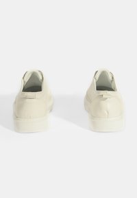Weiße Leder-Slipper mit runder Spitze, strukturiertem Profil und minimalistischem Design. Verfügt über eine kleine Zuglasche an der Ferse für einfaches Anziehen.