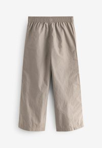 Pantalon court beige clair avec une taille élastique et un tissu lisse et texturé. Pas de poches ni de fermetures visibles.