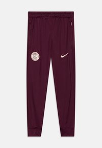 Pantaloni sportivi color marrone, realizzati in un tessuto morbido con vita elasticizzata. Presentano il logo del Paris Saint-Germain e lo swoosh Nike in beige. Due tasche laterali.