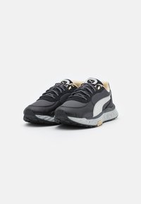 Baskets athlétiques noires avec une tige en mesh texturé, une bande latérale blanche, une semelle intermédiaire moulée et une semelle extérieure en caoutchouc moucheté. Lacets et accents gris foncé.