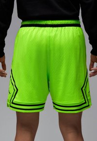 Shorts de sport en mesh respirant de couleur vert néon, avec des accents noirs et une taille élastique noire avec cordon de serrage.