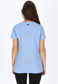 Lys blå kortærmet t-shirt lavet af glat stof. Har en rund halsudskæring og en lille logomærke på ryggen. Tætsiddende pasform.
