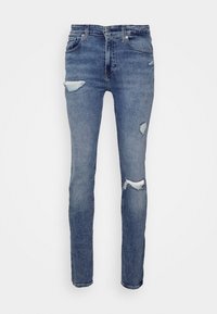 Tajta jeans gjorda av slitstarkt denim. Har en ljusblå färg med flera hål och fransade kanter. Klassisk femfickdesign.