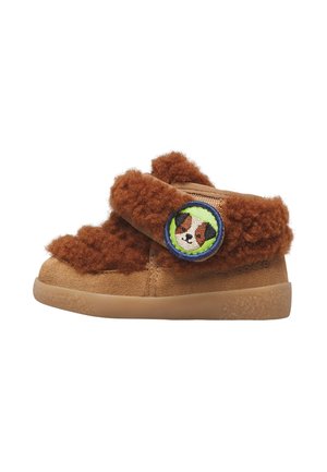 Scarpa marrone per bambino con texture morbida e pelosa e una toppa circolare cucita con la faccia di un cane sulla cinghia laterale.