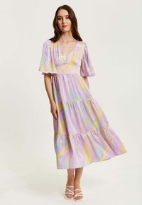 Light purple dress made of soft fabric, featuring a tiered design, flutter sleeves, and multicolored abstract stripes.