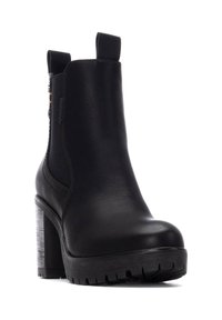 Botines de cuero negro hasta el tobillo con un tacón grueso, plataforma texturizada y paneles laterales elásticos. Presenta un tirador en forma de lazo y un sutil detalle en relieve.