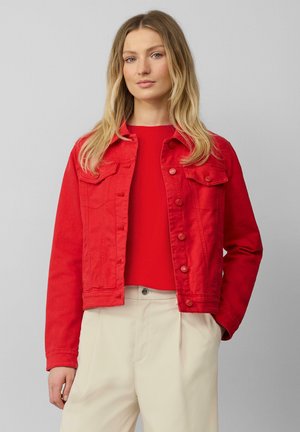 Red denim jacket with button closures, two chest pockets, and a cropped design. The material has a smooth texture, paired with a red top.