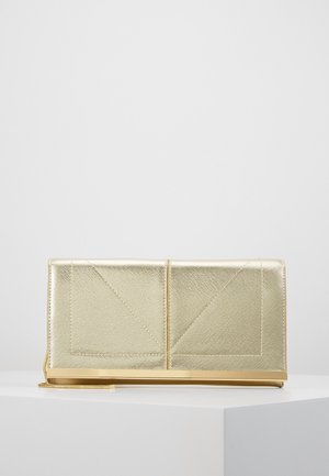 Gouden gestructureerde clutch met geometrische stiksel details en metalen basis, rustend op een wit display oppervlak tegen een effen achtergrond.