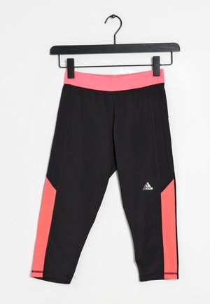 Czarne i różowe krótkie legginsy Adidas wiszące na czarnym wieszaku na białym tle.