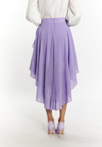Lavender chiffon rok met gelaagde volant, knielengte aan de voorkant en langer aan de achterkant, gecombineerd met bijpassende lavendelkleurige hoge hakken.