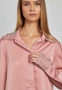 Rosa Satin-Hemd mit dekorativen Strasssteinen an den Schultern und Manschetten, klassischem Kragen und Knopfverschluss vorne.