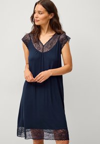 Chemise da notte blu navy con maniche a cappuccio in pizzo e orlo in pizzo delicato. Tessuto morbido e liscio con una vestibilità ampia e scollatura a barca.
