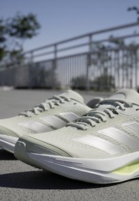 Lichtgroene sportschoenen met een gestructureerde bovenkant, witte gestreepte accenten en een gevoerde zool. Heeft een slank, modern ontwerp.
