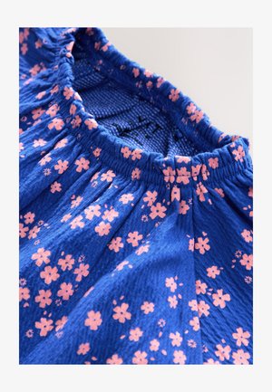 Blåt stof med en rynket halsudskæring, der har spredte rosa blomsterprint over hele stoffet. Tekstureret overflade med en blød finish.