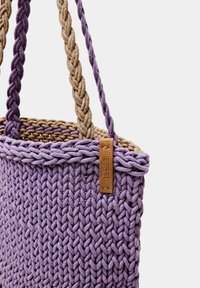 Paarse geweven handtas met gevlochten beige handvatten, met een getextureerd oppervlak en een klein leren label eraan bevestigd.