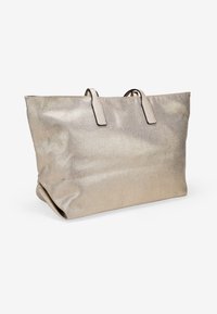 Bolso tote metálico dorado con dos asas en la parte superior, forma rectangular sobredimensionada y una superficie ligeramente texturizada para mayor interés visual.