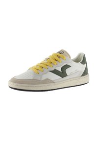 Zapatilla blanca con cordones amarillos, acentos verdes, materiales de ante y cuero, suela texturizada, diseño retro y puntera perforada.