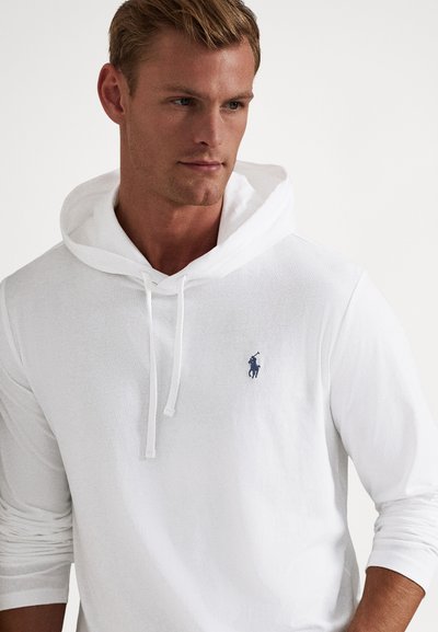 Fehér kapucnis pulóver puha anyagból, kenguruzsebbel, hosszú ujjú, és a mellkas részen egy kis kék hímzett logóval.