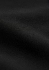 Simai fekete szövet finom, szorosan szőtt textúrával és finom fényvisszaverődéssel, amely lágy redőket alkot.