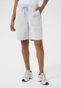 Ljusblå randiga shorts i tyg med dragsko i midjan, sidofickor och uppvikta fållar. Matchas med vita och grå sneakers.