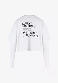 Witte cropped t-shirt met korte mouwen, met op de achterkant zwarte tekst: "DAILY ACTIVE M® STILL RUNNING." Gemaakt van katoen, in een ontspannen pasvorm.