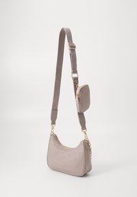 Borsa a spalla in morbido tessuto taupe con una superficie liscia, hardware dorato e una pochette staccabile. Presenta una forma curva e una tracolla regolabile.