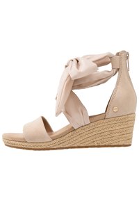Beżowe sandały na koturnie z plecioną platformą z juty, otwarty czubek, materiałowy pasek wokół kostki związany w supeł, z zamkiem błyskawicznym z tyłu.