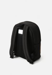 Juodas kuprinės, su paminkštintomis tinklinėmis petnešomis ir lygia išore, su personalizacijos etikete ant nugaros.