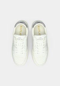 Une paire de baskets blanches de la marque Replay avec des lacets, des embouts perforés et des accents argentés au niveau du talon, vues de dessus sur un fond blanc.