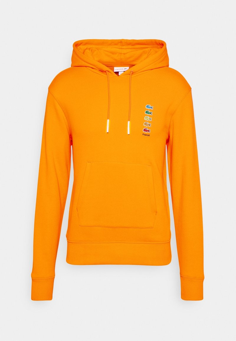 Sweat à capuche orange vif avec poche kangourou à l'avant, capuche à cordon de serrage et petits logos crocodile multicolores sur la poitrine au-dessus du texte "Polaroid".