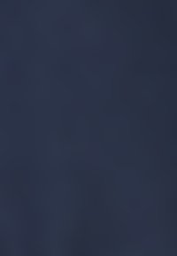 Cielo azzurro con un arcobaleno vivace che si estende sopra una foresta verde e terreni agricoli sotto nuvole diurne.