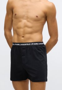 Μαύρα βαμβακερά μπόξερ με λογότυπο στη μέση, διαθέτουν κούμπωμα με κουμπί μπροστά και λείο ύφασμα.