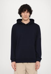 Felpa con cappuccio blu navy realizzata in materiale morbido, dotata di una tasca frontale e di una patch sul manico sinistro, con una vestibilità comoda.