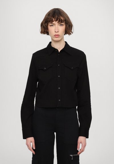 Schwarzes, kurz geschnittenes Hemd mit durchgehender Knopfleiste, zwei Brusttaschen, spitzem Kragen und langen Ärmeln. Glatte Textur und einfarbig.